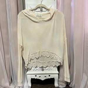 A cream cropped light sweater with lace trim